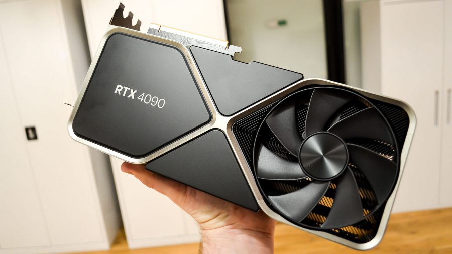 A man's hand holding an Nvidia RTX 4090 in an office
